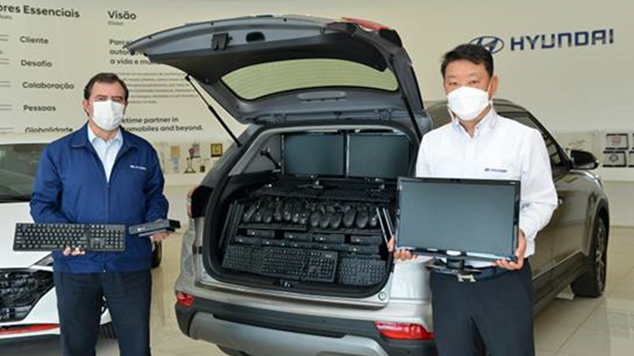 Vice-presidente administrativo da Hyundai, Young Duk Han, e diretor executivo de Produção, Marcos Oliveira, embarcam todos os 25 computadores no porta-malas de um SUV Hyundai Creta usado especialmente para a logística da entrega da doação